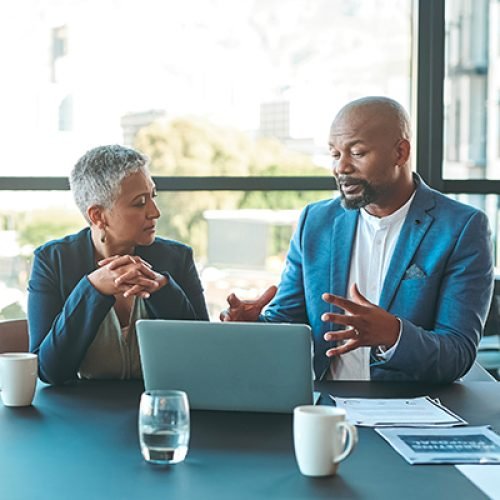 Business, presentation and man on a laptop in a corporate conference or office collaboration with a woman at work. Businessman, manager or coach for marketing, strategy and sales working with CEO.